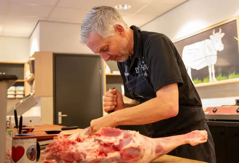 Slager die stuk vlees snijdt